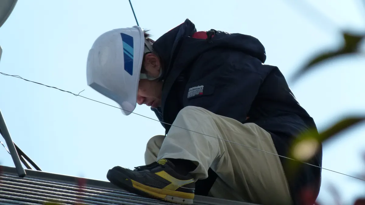 Operario con casco trabajando agachado sobre una cubierta durante una instalación solar